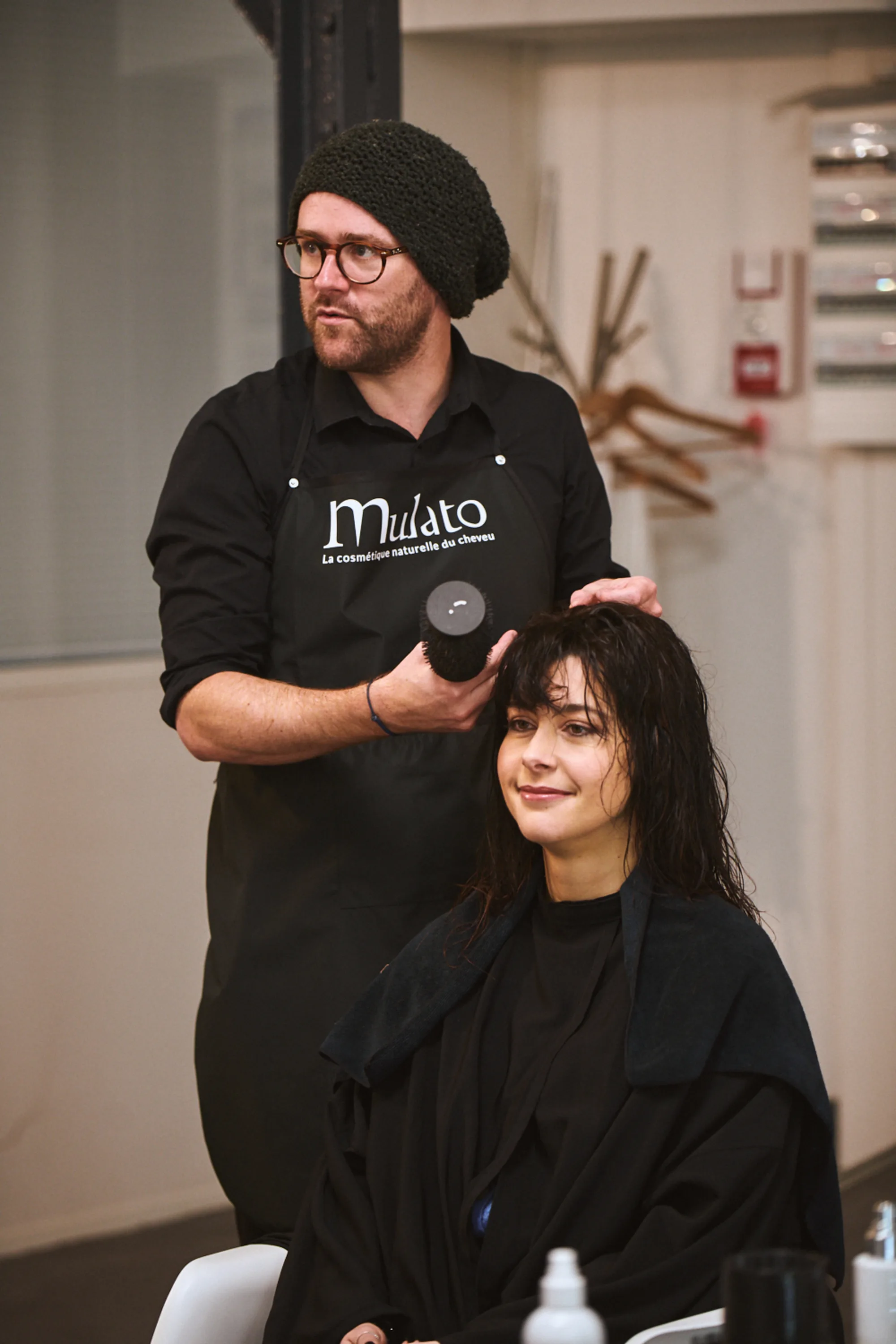 Coiffeur en tablier Patrice Mulato qui conseille une cliente devant le miroir