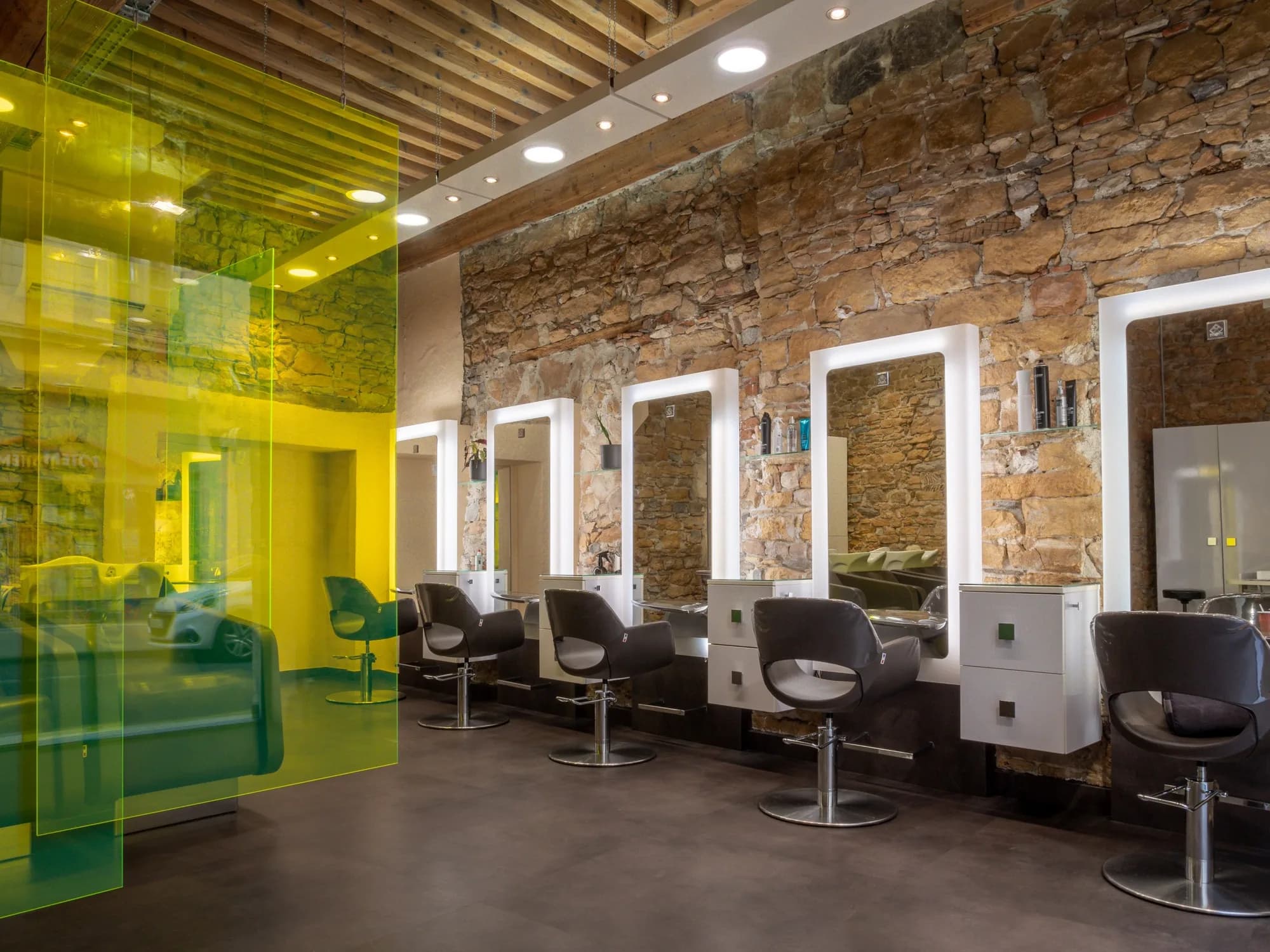 L'intérieur du Salon Bo. : murs en pierre dorée, plafond à poutres et cloisons en verre vert chartreuse