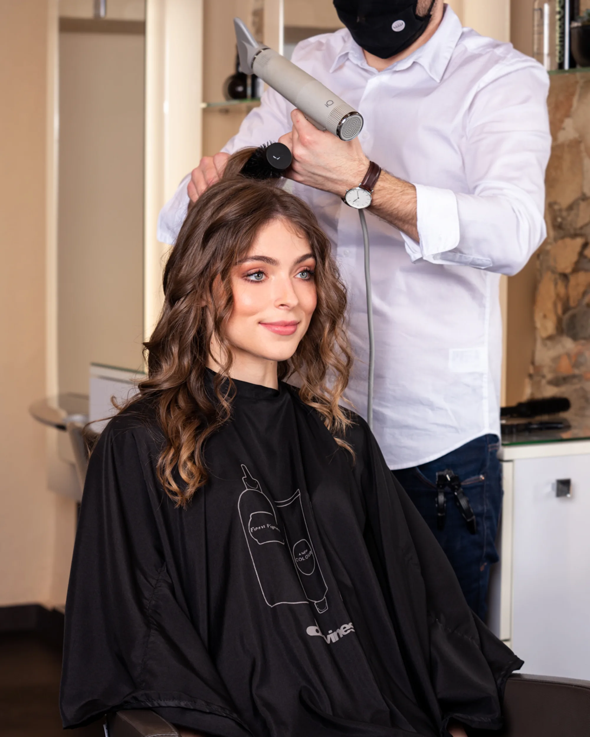 Coiffeur qui sèche des boucles brunes au sèche-cheveux